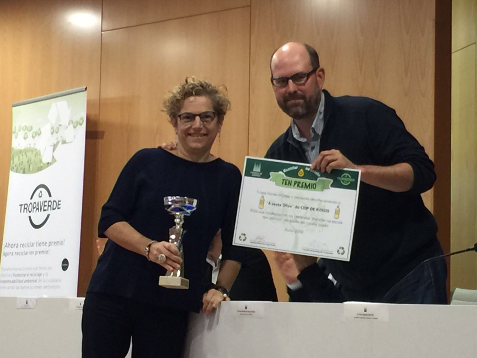 Martiño Noriega entrega o 1º premio da recollida de aceites á directora do CEIP de Roxos, Eva García, polo traballo realizado pola aula "A sexta oliva".
